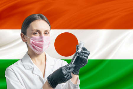 Girl doctor prepares vaccination against the background of the Niger flag. Vaccination concept Niger.の写真素材
