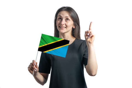 Happy young white woman holding flag of Tanzania and points thumbs up isolated on a white background.の写真素材