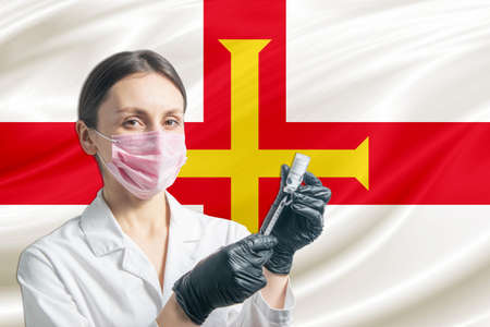 Girl doctor prepares vaccination against the background of the Guernsey flag. Vaccination concept Guernsey.の写真素材