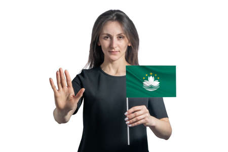 Happy young white woman holding flag of Macau and with a serious face shows a hand stop sign isolated on a white background.の写真素材