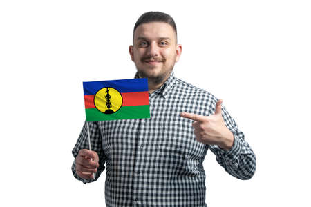 White guy holding a flag of New Caledonia and points the finger of the other hand at the flag isolated on a white background.の写真素材