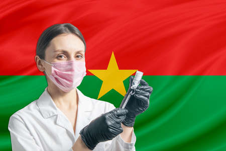 Girl doctor prepares vaccination against the background of the Burkina Faso flag. Vaccination concept Burkina Faso.の写真素材
