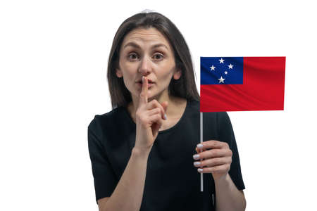 Happy young white woman holding flag of Samoa and holds a finger to her lips isolated on a white background.の写真素材