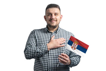 White guy holding a flag of Serbia and holds his hand on his heart isolated on a white background With love to Serbia.の写真素材