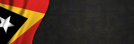 East Timor flag on concrete wall. Banner with fabric texture of the flag of East Timor.の写真素材