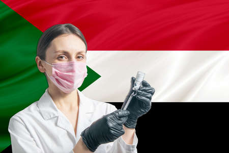 Girl doctor prepares vaccination against the background of the Sudan flag. Vaccination concept Sudan.の写真素材