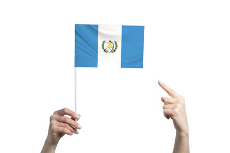 A beautiful female hand holds a Guatemala flag to which she shows the finger of her other hand, isolated on white background.の写真素材