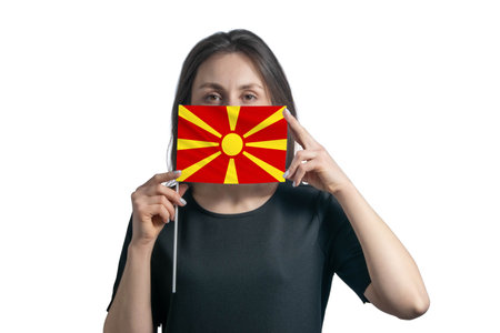 Happy young white woman holding flag Northern Macedonia flag and covers her face with it isolated on a white background.の写真素材