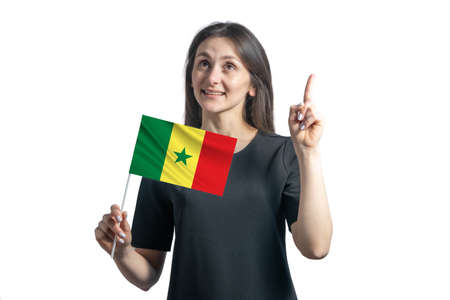 Happy young white woman holding flag of Senegal and points thumbs up isolated on a white background.の写真素材