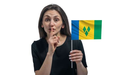 Happy young white woman holding flag of Saint Vincent and the Grenadines and holds a finger to her lips isolated on a white background.の写真素材