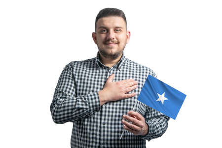 White guy holding a flag of Somalia and holds his hand on his heart isolated on a white background With love to Somalia.の写真素材