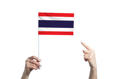 A beautiful female hand holds a Thailand flag to which she shows the finger of her other hand, isolated on white background.の写真素材