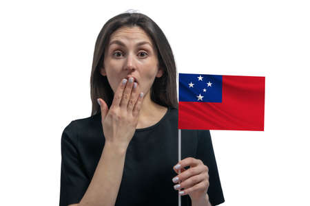 Happy young white woman holding flag of Samoa and covers her mouth with her hand isolated on a white background.の写真素材