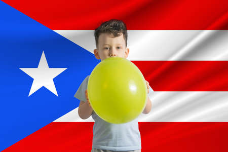 Children's day in Puerto Rico. White boy with a balloon on the background of the flag of Puerto Rico. Childrens day celebration concept.の写真素材