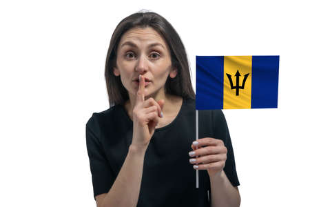 Happy young white woman holding flag of Barbados and holds a finger to her lips isolated on a white background.の写真素材
