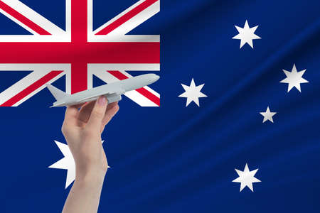 Airplane in hand with national flag of Australia. Travel to Australia.の写真素材