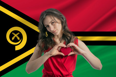 Love Vanuatu. A girl holds a heart on her chest in her hands against the background of the flag of Vanuatu. The concept of patriotismの写真素材
