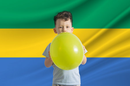 Children's day in Gabon. White boy with a balloon on the background of the flag of Gabon. Childrens day celebration conceptの写真素材
