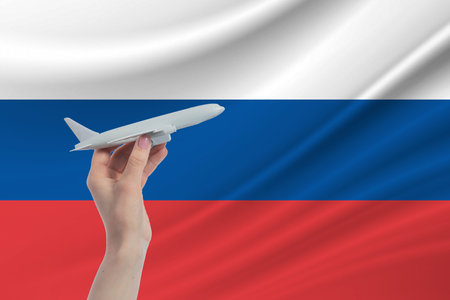 Airplane in hand with national flag of Russia. Travel to Russia.