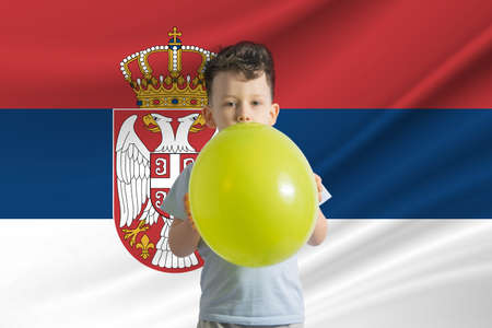 Children's day in Serbia. White boy with a balloon on the background of the flag of Serbia. Childrens day celebration conceptの写真素材