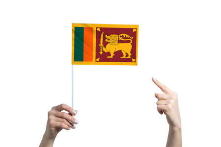 A beautiful female hand holds a Sri Lanka flag to which she shows the finger of her other hand, isolated on white background.の写真素材