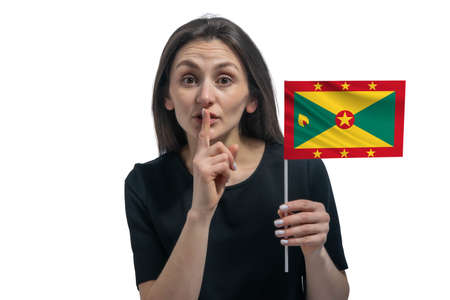 Happy young white woman holding flag of Grenada and holds a finger to her lips isolated on a white background.の写真素材