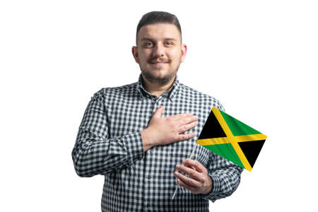 White guy holding a flag of Jamaica and holds his hand on his heart isolated on a white background With love to Jamaica.の写真素材