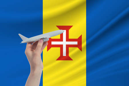 Airplane in hand with national flag of Madeira. Travel to Madeira.の写真素材