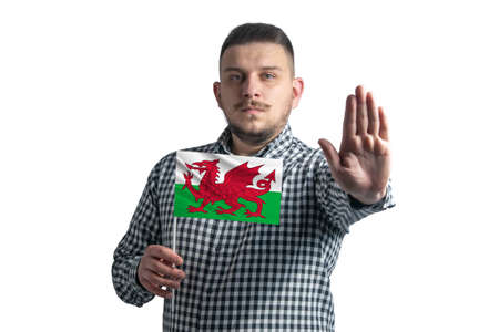 White guy holding a flag of Wales and with a serious face shows a hand stop sign isolated on a white background.の写真素材