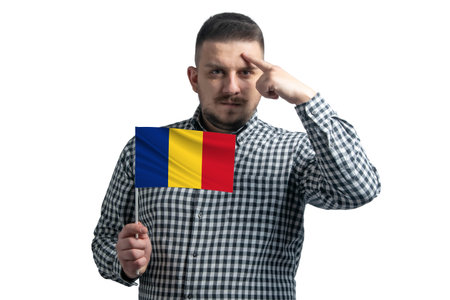 White guy holding a flag of Romania and a finger touches the temple on the head isolated on a white background.の写真素材