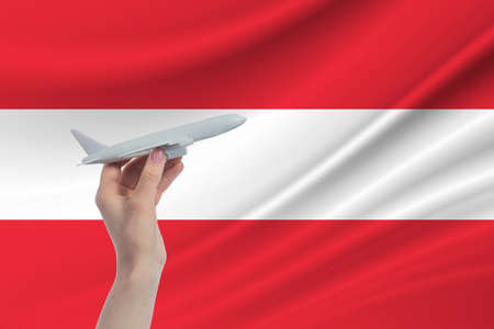 Airplane in hand with national flag of Austria. Travel to Austria.の写真素材