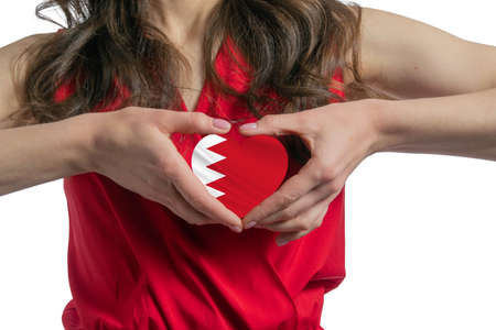 Love Bahrain. The woman holds a heart in the form of the flag of Bahrain on her chest. Concept of patriotism.の写真素材