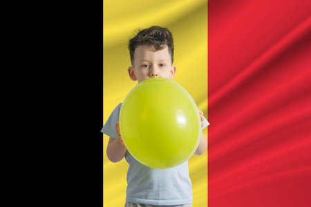 Children's day in Belgium. White boy with a balloon on the background of the flag of Belgium. Childrens day celebration concept.の写真素材