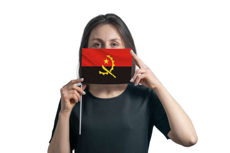 Happy young white woman holding flag Angola flag and covers her face with it isolated on a white background.の写真素材
