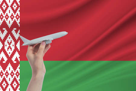 Airplane in hand with national flag of Belarus. Travel to Belarus.の写真素材