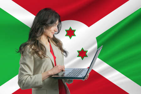 Freelance in Burundi. Beautiful young woman freelancer uses laptop computer against the background of the flag of Burundi.の写真素材