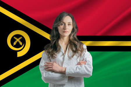Medicine in Vanuatu. Happy beautiful female doctor in medical coat standing with crossed arms against the background of the flag of Vanuatu.の写真素材