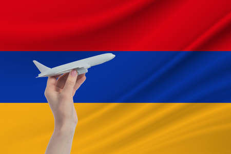 Airplane in hand with national flag of Armenia. Travel to Armenia.の写真素材