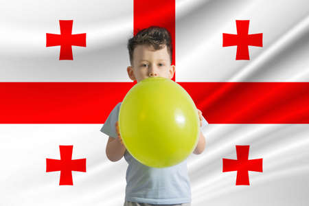 Children's day in Georgia. White boy with a balloon on the background of the flag of Georgia. Childrens day celebration concept.の写真素材
