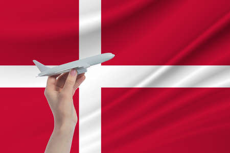 Airplane in hand with national flag of Denmark. Travel to Denmark.の写真素材