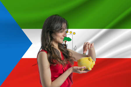 Economy in Equatorial Guinea Accumulating and saving money in Equatorial Guinea Woman putting money coin in piggy bank for saving money and plan finance.の写真素材
