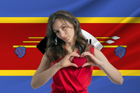 Love Esvatini A girl holds a heart on her chest in her hands against the background of the flag of Esvatini The concept of patriotism.の写真素材