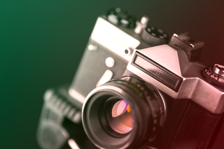 Old analog camera in black and silver tones. The camera is photographed on a dark blurred background.の写真素材