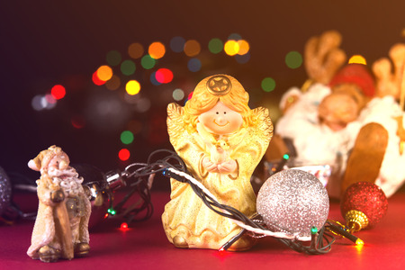 Ceramic white Christmas angel with a dove in his hands. In the background lights of different colors.の写真素材