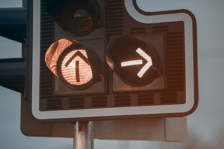 Black new traffic light with arrows. Photographed in the dark. The background is blurred.の写真素材