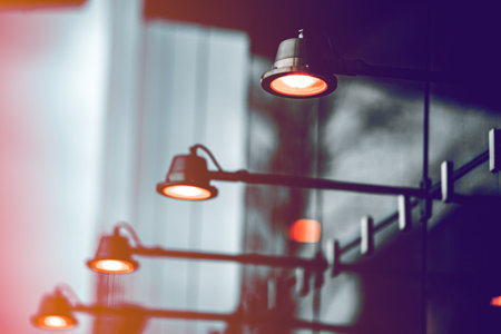 Illuminating lamps of dark color on a modern building. The facade of the building is made of glass.の写真素材
