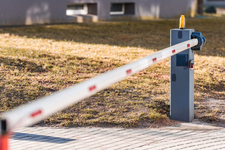 Automatic barrier white and red. The barrier is closed. The background is blurred. Shallow depth of...