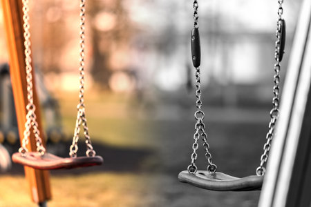 Children's swing made of shiny iron chain. The background is blurred. Swing on the Playground.