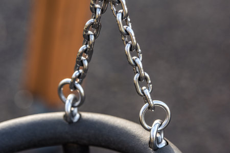 Children's swing made of shiny iron chain. The background is blurred. Swing on the Playground.