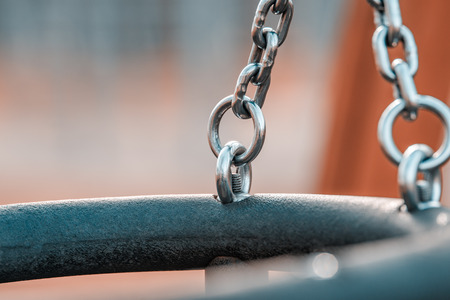 Children's swing made of shiny iron chain. The background is blurred. Swing on the Playground.の写真素材
